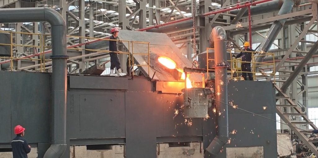 Workers pouring molten steel from ladle into sand molds with sparks flying at ZHILI foundry workshop